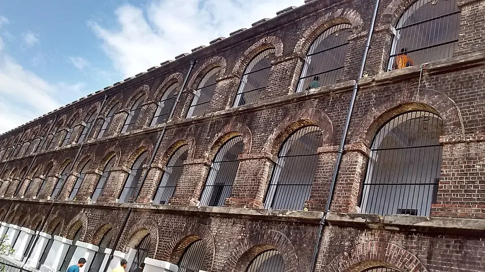 Rows of barred cell openings along a brick wing of Cellular Jail
