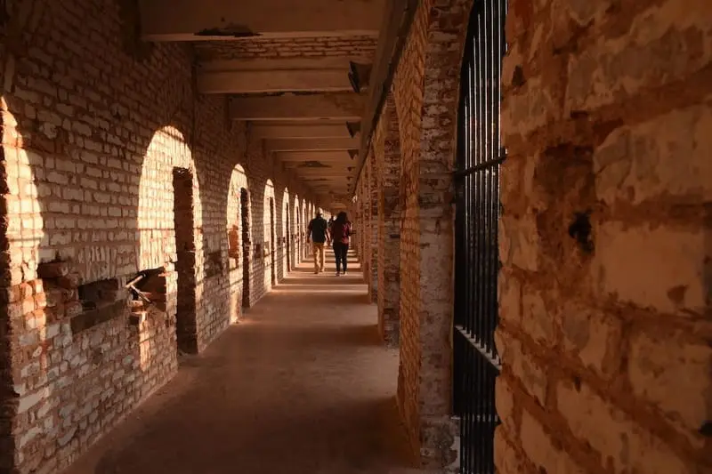 Long brick corridor with barred cell doors inside a surviving wing of Cellular Jail